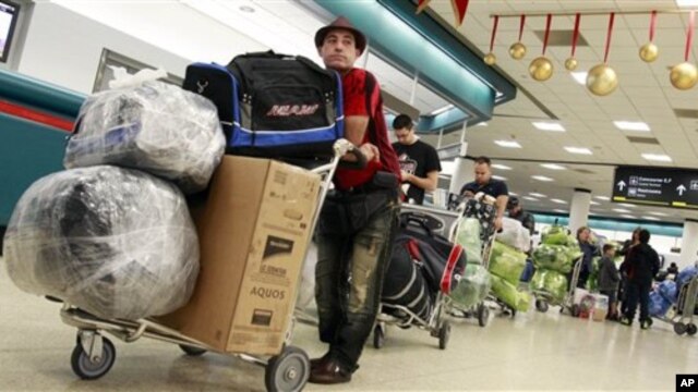 Travelers wait in line to check in as they prepare to travel to Cuba at Miami International Airport in Miami, 23 Dec 2010
