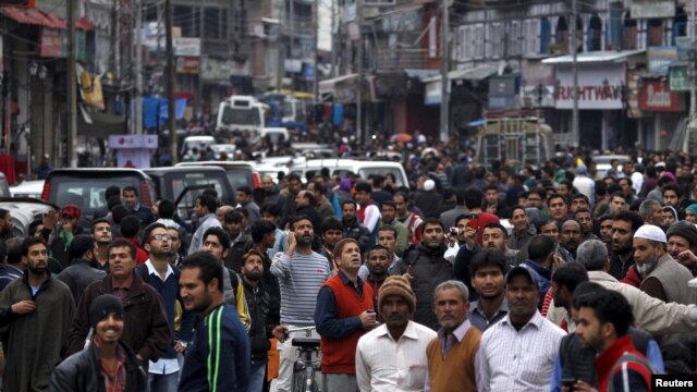 People stand on a road after vacating buildings following an earthquake in Srinagar, October 26, 2015.