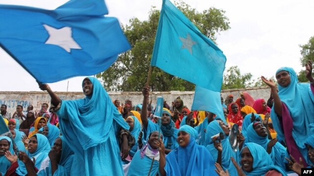Somali women wave their national flag at Konis stadium, in Mogadishu, during a ceremony marking the anniversary of Somalia’s independence, July 1, 2012. 