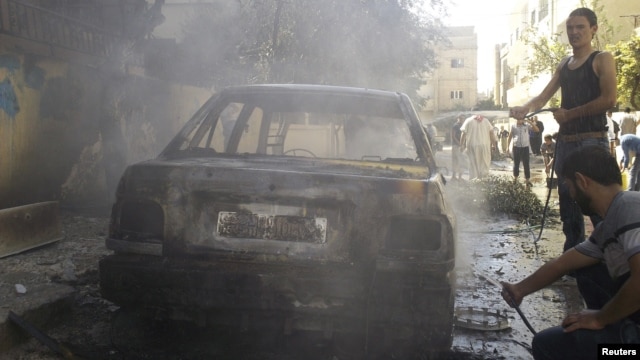 Residents stand next to a damaged car after shelling by forces loyal to Syria's President Bashar al-Assad at al-Saad near Deraa, November 3, 2012. 