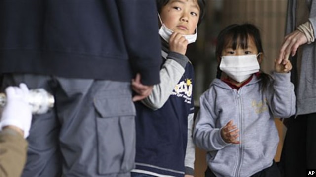 Children watch their father is screened for radiation at a shelter in Fukushima prefecture, Japan, March 29, 2011