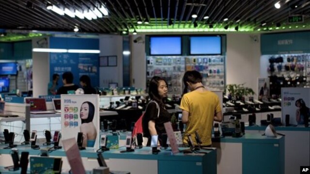 A couple shop for mobile phones in Beijing.  China's trade surpluses have brought economic gains, but political reform has not kept up.  