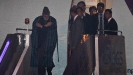 Afghanistan President Hamid Karzai, left, is escorted by officials as he walks out of an airplane upon his arrival in Beijing for the Shanghai Cooperation Organization (SCO) summit, June 5, 2012.