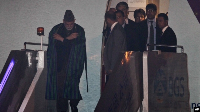 Afghanistan President Hamid Karzai, left, is escorted by officials as he walks out of an airplane upon his arrival in Beijing for the Shanghai Cooperation Organization (SCO) summit, June 5, 2012.
