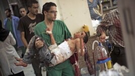 A doctor carries a severely wounded Syrian boy in the Dar El Shifa hospital, in Aleppo, Syria, Oct. 4, 2012 after the child was hit by Syrian Army shelling. 