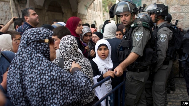 Palestinian Muslim worshippers wait as Israeli border guards have their documents and belongings checked at the entrance of al-Aqsa mosque compound in Jerusalem's Old city, April 20, 2014.