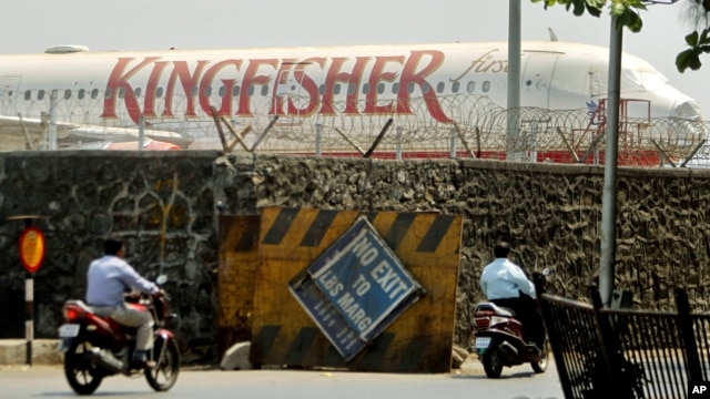Commuters drive past a stationary aircraft belonging to Kingfisher airlines at the domestic airport in Mumbai, India, March 20, 2012.