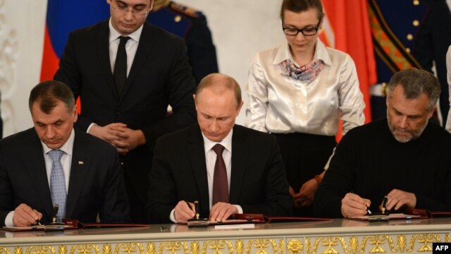 Russia's President Vladimir Putin (C),  Crimean parliament speaker Vladimir Konstantionov (L)  and Aleksei Chalov, Sevastopol's new de facto mayor (R), sign a treaty to make Crimea part of Russia in Moscow on March 18, 2014. 