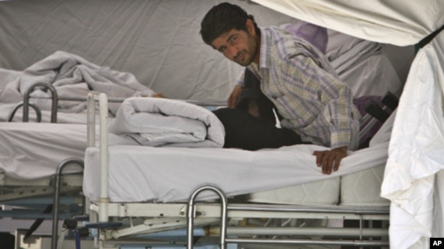 A Syrian refugee waits for medical assistance on a bed in a field hospital set up by the Turkish Health Ministry in a camp in Yayladagi ,Turkey, near the Syrian border, Sunday, June 12, 2011.