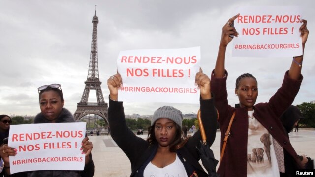 Những người phụ nữ giơ cao biểu ngữ với nội dung "Bring back our girls", tạm dịch "Đưa những cô gái quay trở lại" trong một cuộc biểu tình gần tháp Eiffel ở Paris, 13/5/2014.