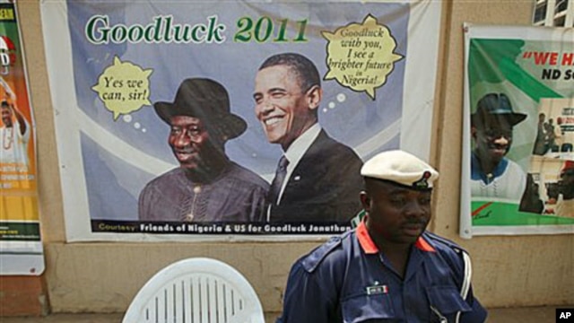 A Nigerian security man sits under a campaign poster of Nigeria President Goodluck Jonathan, with US President Barrack Obama, in Abuja, Nigeria, January 12, 2011