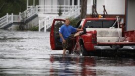 A Mississippi man lifts his left leg to remove water from his boot after wading through Isaac's flood waters 
