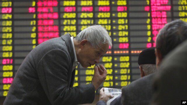 An investor gestures to another in front of the stock price monitor at a private securities company in Shanghai, China, November 22, 2012.