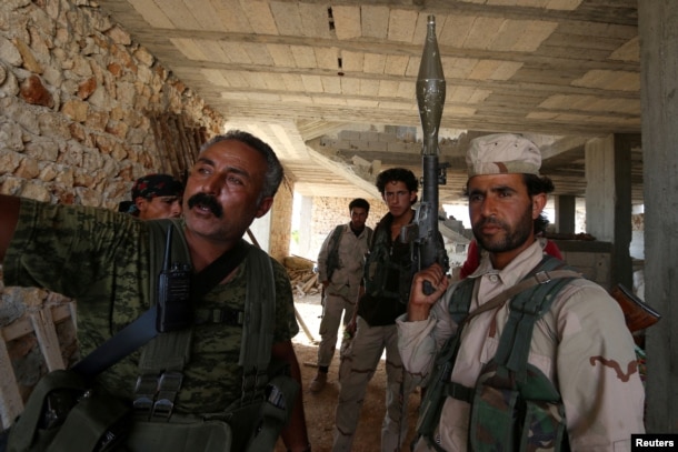 FILE - Fighters of the Syria Democratic Forces (SDF) stand inside a building near Manbij, in Aleppo Governorate, Syria on June 17, 2016.