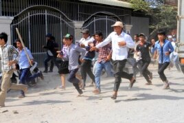 Cambodian garment workers run as they escape for safety in front of a factory of Yak Jin in Kambol village on the outskirts of Phnom Penh, Cambodia, Thursday, Jan. 2, 2014.