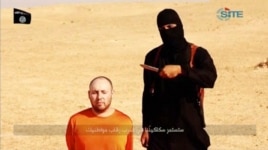 FILE - A masked, black-clad militant, identified by The Washington Post newspaper as a Briton named Mohammed Emwazi, stands next to a man purported to be Steven Sotloff in this still image from a video obtained from SITE Intel Group website, Feb. 26, 2015.