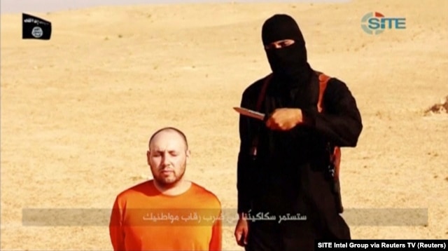 FILE - A masked, black-clad militant, identified by The Washington Post newspaper as a Briton named Mohammed Emwazi, stands next to a man purported to be Steven Sotloff in this still image from a video obtained from SITE Intel Group website, Feb. 26, 2015