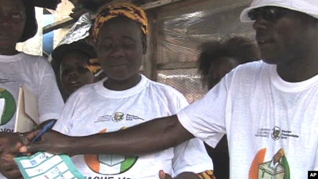 Educators teach female street vendors how to properly fold a ballot after marking their candidate so the ink will not smudge into multiple boxes, rendering the vote invalid