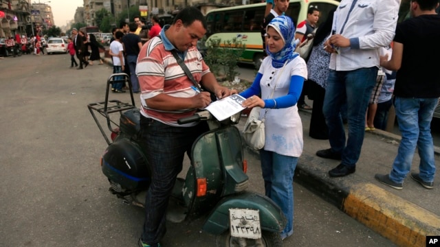An Egyptian signs a petition for Tamarod, Arabic for "rebel", a campaign calling for the ouster of Egyptian President Mohammed Morsi and for early presidential elections in the Shubra neighborhood in Cairo, Egypt, June 2, 2013. 