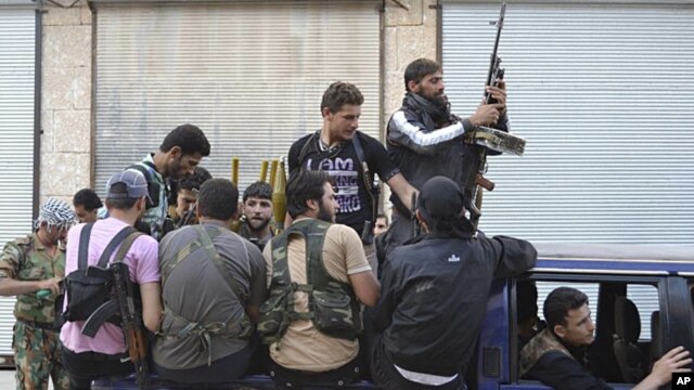 This citizen journalism image provided by Edlib News Network (ENN), purports to show Syrian rebels gathered on their vehicle in the northern town of Kfar Nebel, in Idlib province, Syria, June 5, 2012.