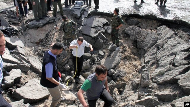 Enspektè siryen sou plas apre yon eskplozyon kraze biwo sèvis sekrè a nan Damas  -- 10 me 2012 (Foto VOA).
