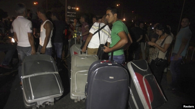 Passengers carrying baggage try to pass, after main road leading to Beirut airport was blocked by relatives of the 11 Lebanese Shi'ite pilgrims who were abducted in Syria, August 15, 2012. 