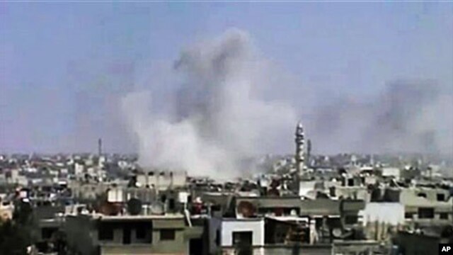 In this image from an amateur video and released by the Syrian Media Council, smoke rises following purported shelling in Homs, Syria, April 10, 2012.
