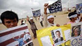 Residents who face eviction from their homes display signs with pictures of U.S. President Barack Obama and Secretary of State Hillary Clinton, as they ask for help in protecting their rights during a protest ahead of their visit in Phnom Penh November 18.
