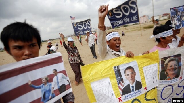 Residents who face eviction from their homes display signs with pictures of U.S. President Barack Obama and Secretary of State Hillary Clinton, as they ask for help in protecting their rights during a protest ahead of their visit in Phnom Penh November 18