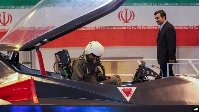 Iranian President Mahmoud Ahmadinejad, center, listens to an unidentified pilot during a ceremony to unveil Iran's newest fighter jet, Qaher-313, or Dominant-313,which officials claim can evade radar, in Tehran, February 2, 2013.