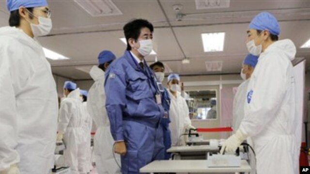 Perdana Menteri baru Jepang, Shinzo Abe (tengah), berbincang dengan pekerja di Pusat Operasi Darurat Tokyo Electric Power Co.(TEPCO) di PLTN Okuma, Fukushima, Jepang (29/12).