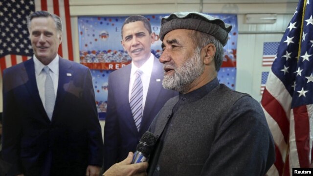 Afghan journalist Abdul hai Warshan talks during an interview in front of cardboard cut-outs of U.S. President Barack Obama and Republican presidential candidate Mitt Romney at the U.S. embassy in Kabul, November 7, 2012.
