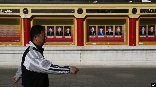 A man walks past portrait of communist party members on display outside Imperial Ancestral Temple in Beijing, China, November 12, 2012.