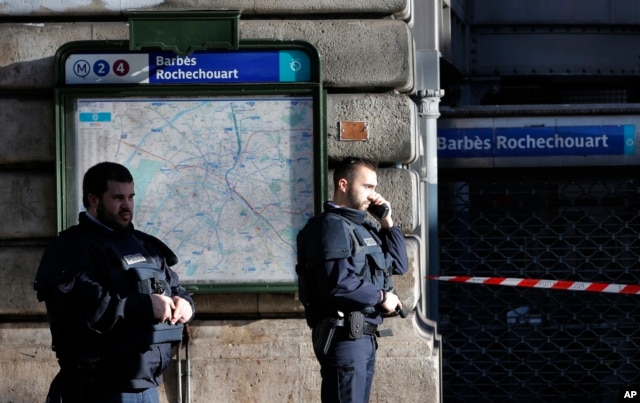 Police officers secure the area after a fatal shooting which took place at a police station in Paris, Jan. 7, 2016.