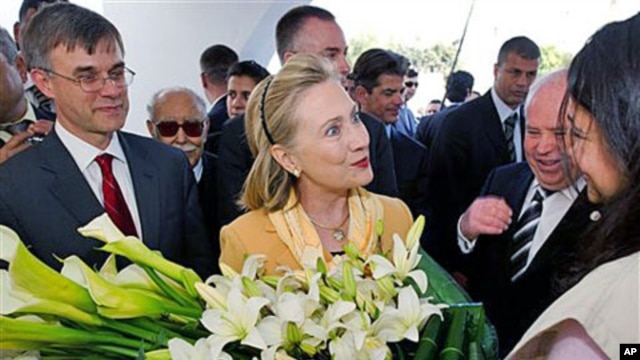 US Secretary of State Hillary Clinton is presented flowers as she tours the Red Crescent with US Ambassador to Tunisia Gordon Grey, left, in Tunis, March, 17, 2011