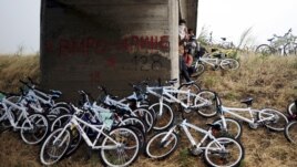 Syrian immigrants traveling by bicycle take shelter from the rain beneath a bridge near the Greek border with Macedonia, June 17, 2015.