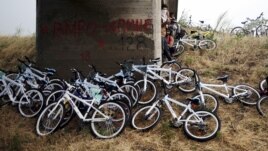 Immigrants from Syria stand near their bicycles as they hide from the rain under a bridge near the Greek border with Macedonia, June 17, 2015.