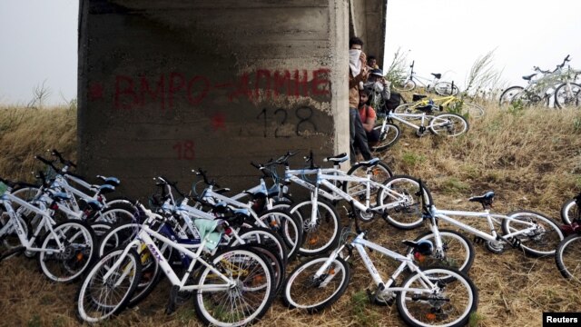 Syrian immigrants traveling by bicycle take shelter from the rain beneath a bridge near the Greek border with Macedonia, June 17, 2015.