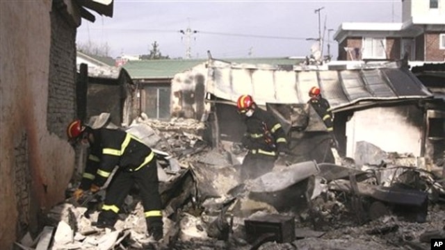 South Korean firefighters inspect destroyed houses on Yeonpyeong island, South Korea, 24 Nov 2010