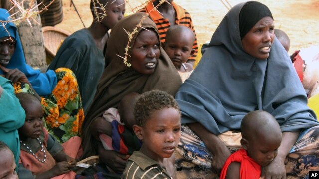 FILE - Somali women and children sit under a tree at a refugee camp in Dolo, Somalia. Relief agencies say 300,000 children under 5 can no longer get vaccinated against major childhood killers like measles or treated for diarrhea.