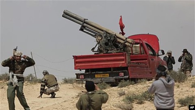 Libyan rebels prepare to fire a rocket launcher at the front line outside Brega, April 2, 2011