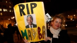 A woman with a banner pays tribute to Nelson Mandela outside the South African High Commission in London, Dec. 6, 2013.