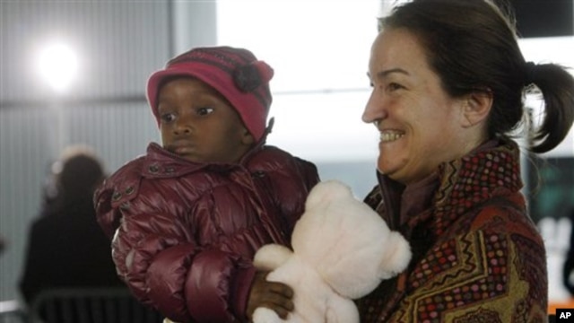 A French adoptive parent carries an orphan from Haiti at Roissy airport, outside of Paris, 22 Dec 2010