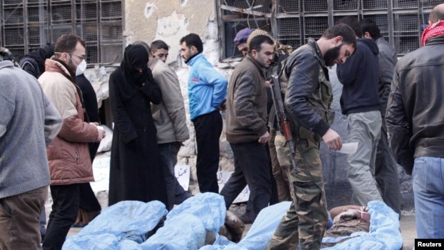 Free Syrian Army fighters and residents attempt to identify bodies found along a river, at a school used as a field hospital in Aleppo, Syria, January 29, 2013