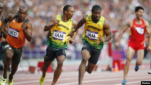 Jamaica's Yohan Blake (2nd R) takes the baton from teammate Michael Frater (2nd L) next to Netherlands' Giovanni Codrington (L) during the men's 4x100m relay round at the Olympic Stadium, August 10, 2012. 