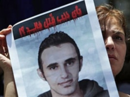 An activist carries a picture of slain Khaled Said with Arabic that reads "Why was Khaled killed?" during a protest at the Egyptian Journalists Syndicate in Cairo, June 19, 2010