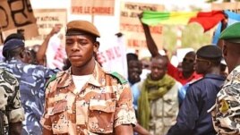 A national guard soldier walks by demonstrators at Bamako airport, Mali. (VOA - N. Palus)
