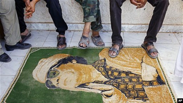 Libyan rebels use a carpet with the image of Moammar Gadhafi as a doormat at their camp, set up in a district of Gadhafi sympathizers in the stronghold city of Tarhouna, 100 kilometers southeast of Tripoli, Libya, August 29, 2011