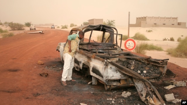 A man takes a close look at a burned-out truck in Timbuktu, Mali, January 31, 2013. 