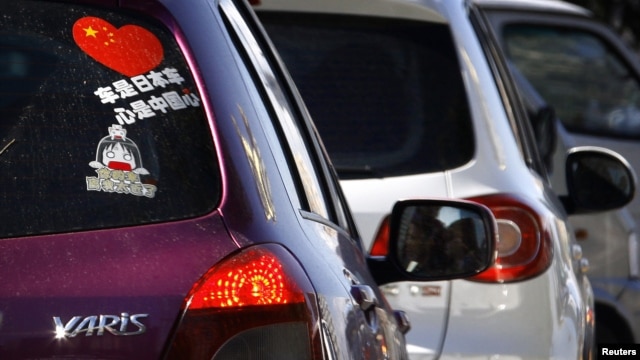 A Toyota car with a sticker attached to the rear window reading 'Japanese car, Chinese heart' is seen along a main road in central Beijing, October 9, 2012.